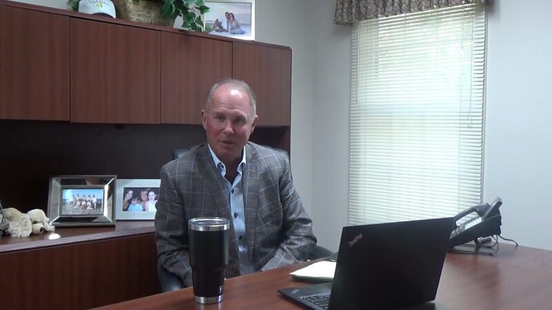Sean Denny at his desk, speaking to camera about client outcomes